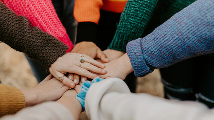 Group of hands on top of eachother wearing different coloured clothing and jewelry 700jpg.jpg